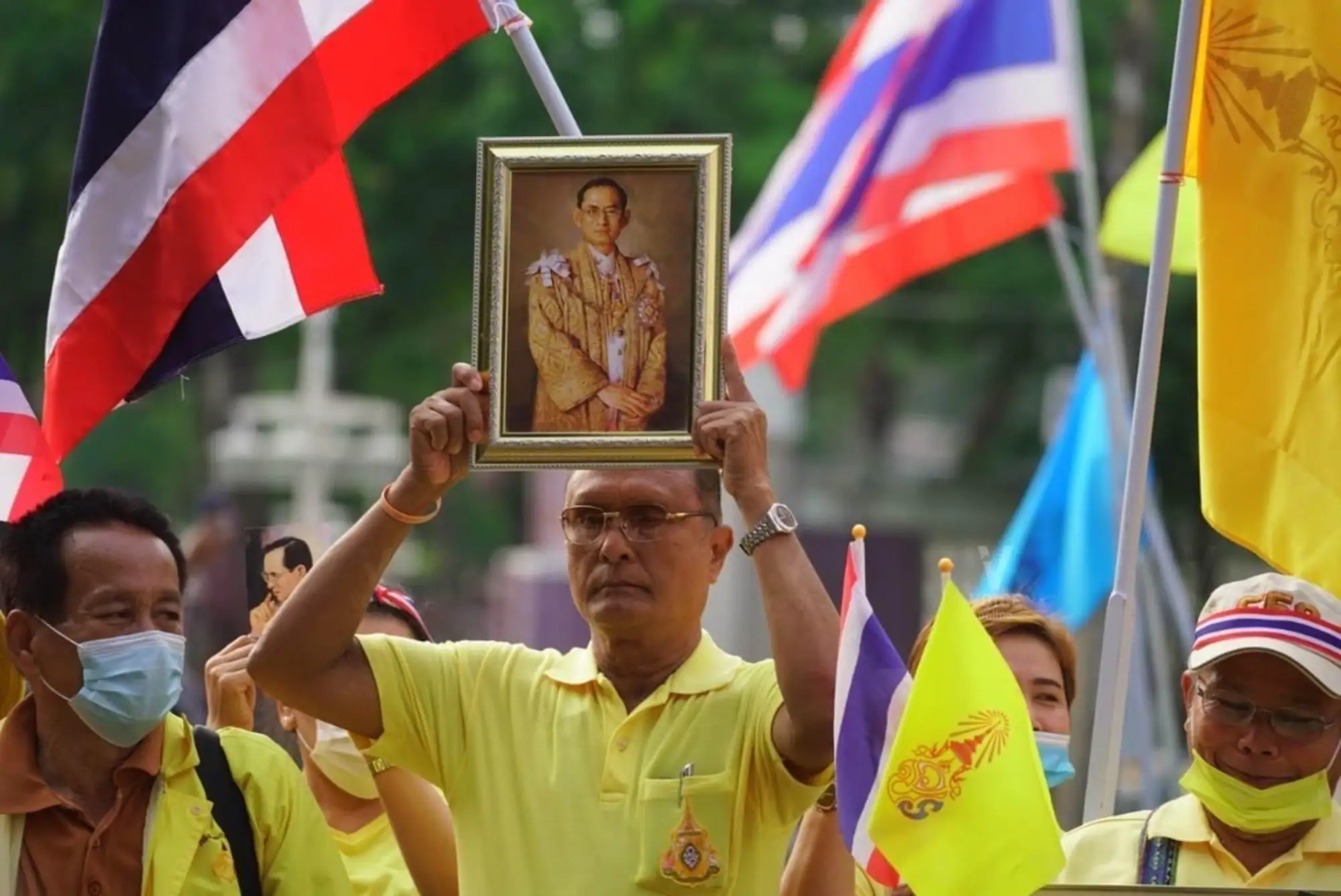 穿著黃衫的泰國保王派民眾手持旗幟與王室照片，表明支持君主立憲制的決心（圖片來源：Voice TV）