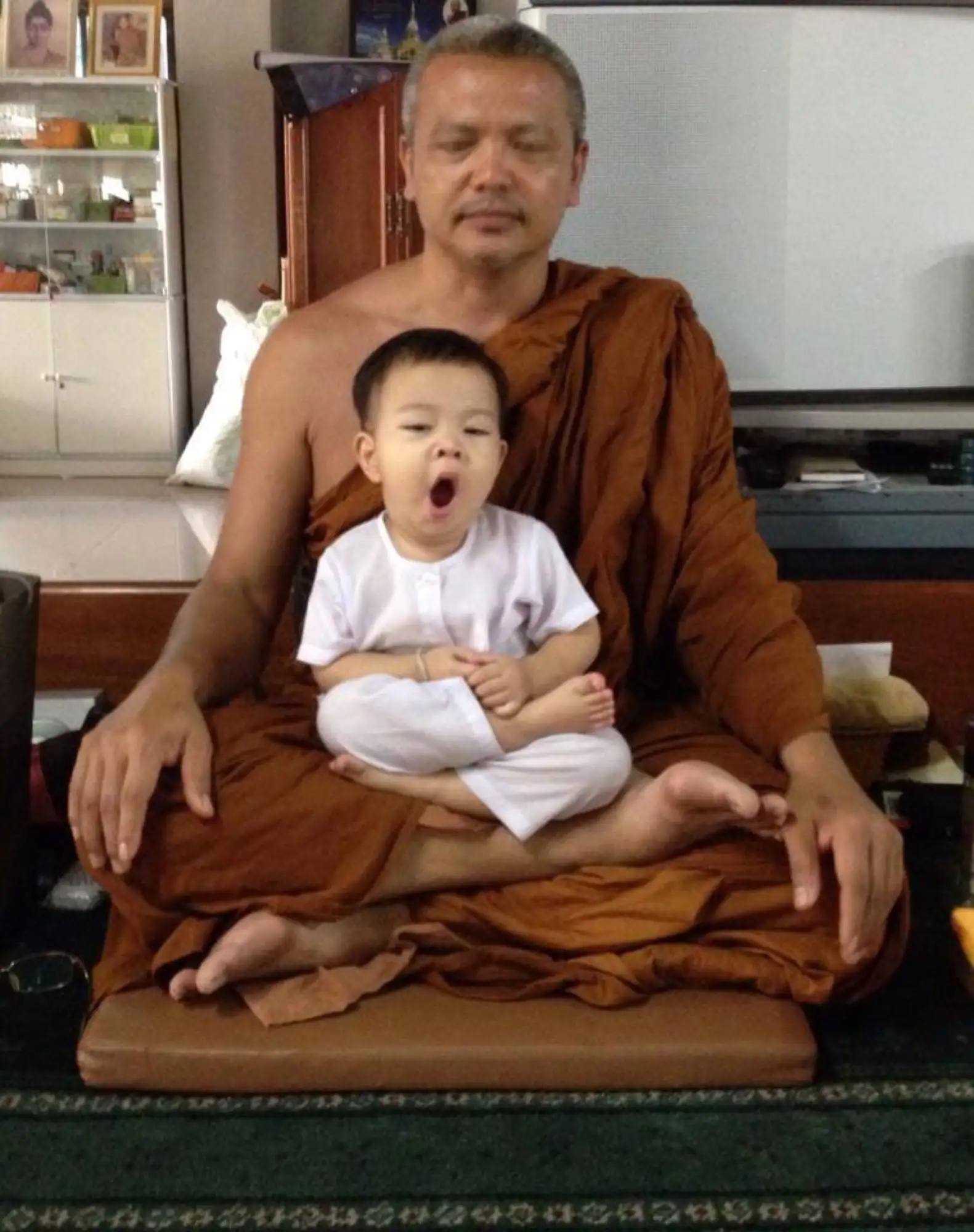 泰國小和尚Nongkorn因為年紀太小了，以至於師傅在講道的時候，他總是止不住困意，打瞌睡或直接躺在師傅懷裡睡覺（圖片來源：粉專頁）