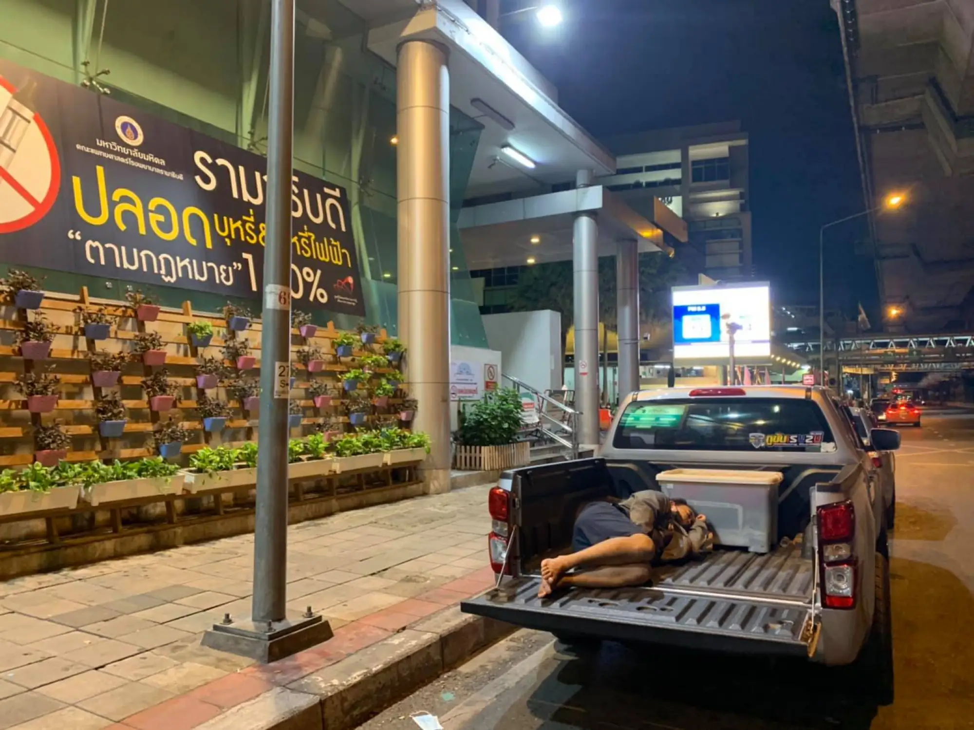 曼谷醫院門口聚集許多戴著口罩的民眾，排隊等候治療，累了就打瞌睡或躺在車上休息。(圖片來源：FB@thiravat.h)