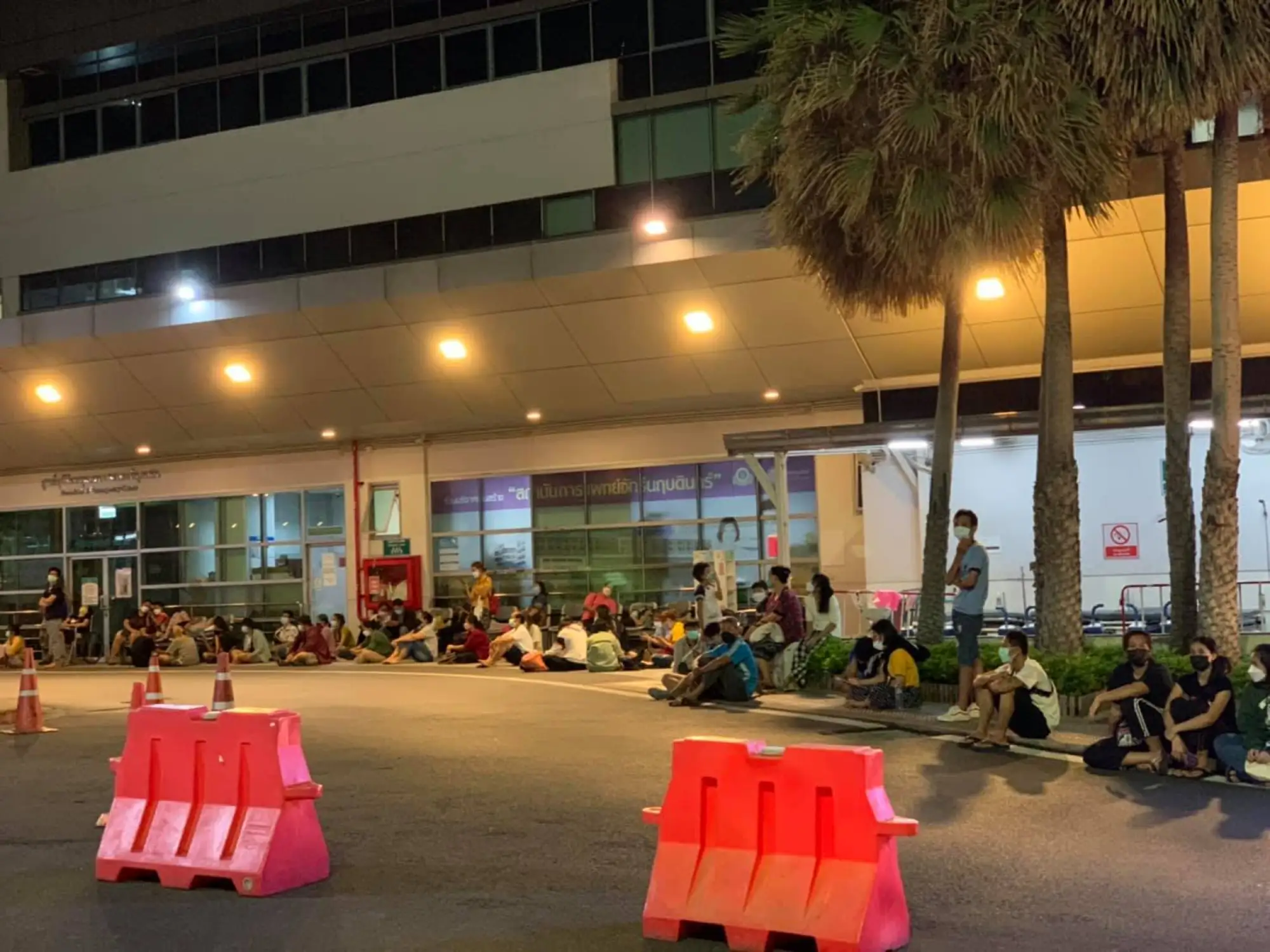 拉瑪提波迪醫院(Ramathibodi Hospital)外可見數十名戴著口罩的民眾，坐在醫院外漏夜等候床位(圖片來源：FB@thiravat.h)