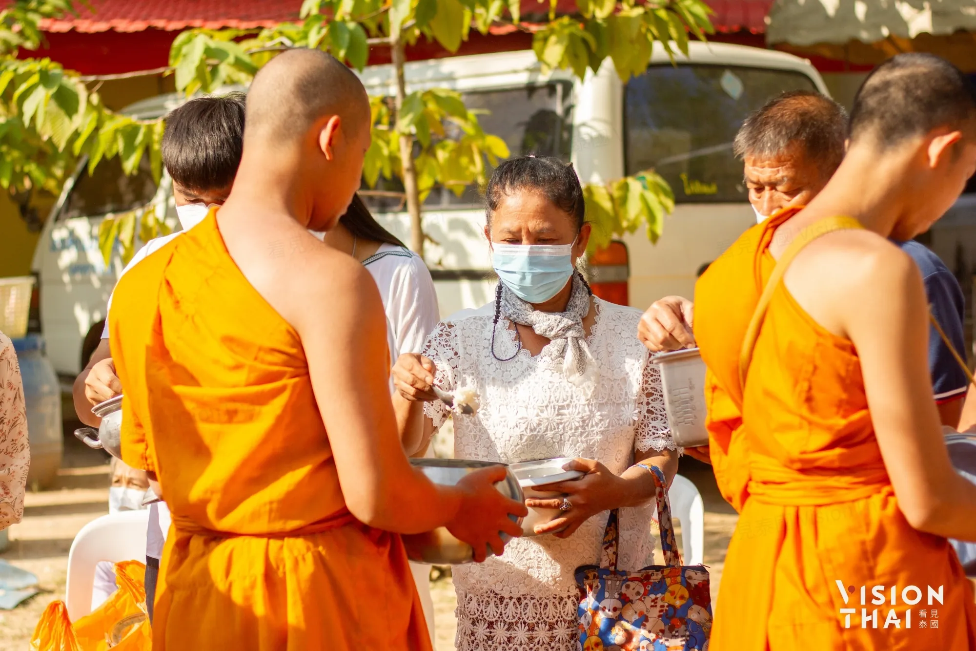 走入泰国在地生活体验清晨布施仪式，将食物放入钵中并低头领受僧侣诵经祝福。（来源：看见泰国 VisionThai）